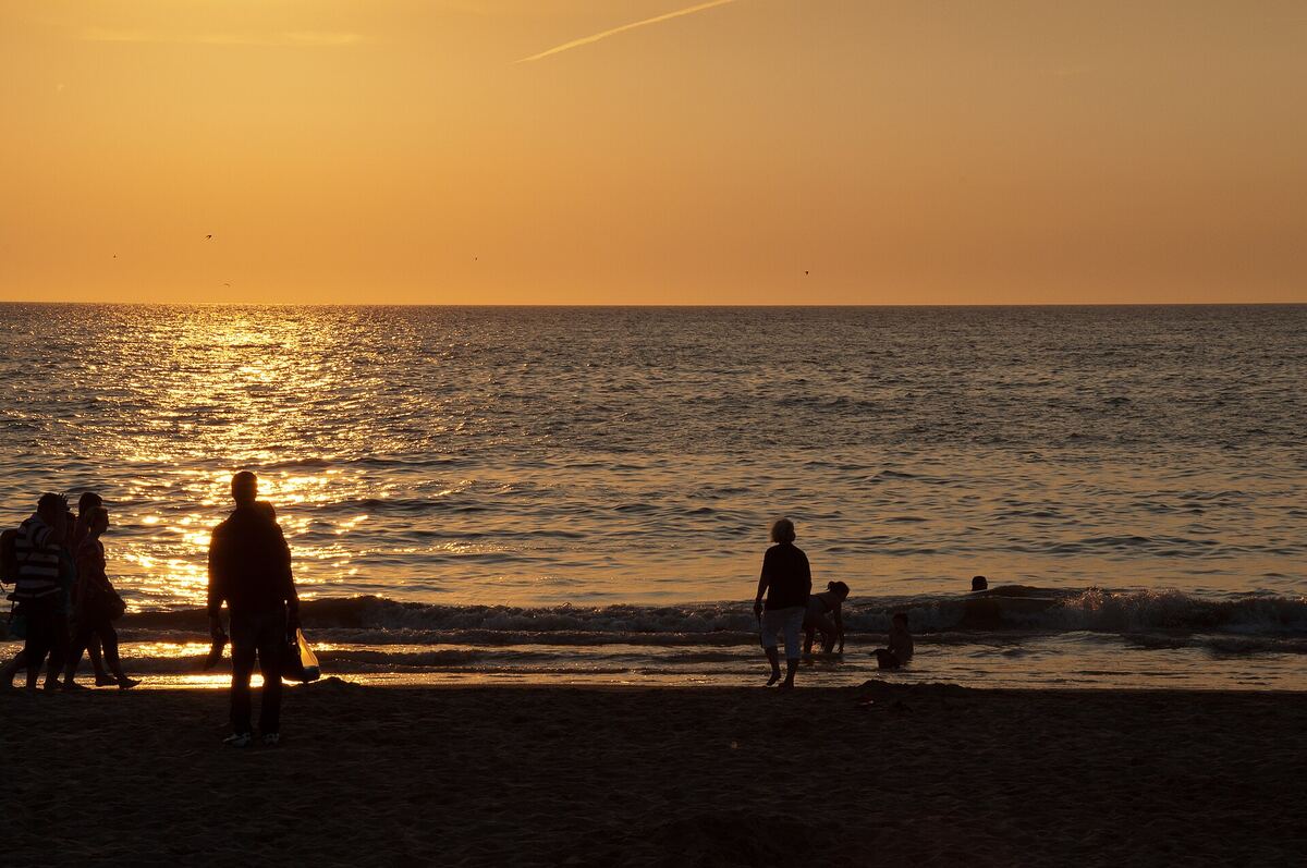 Silhouetten van strandgangers bij zonsondergang aan het strand van Noordwijk aan Zee